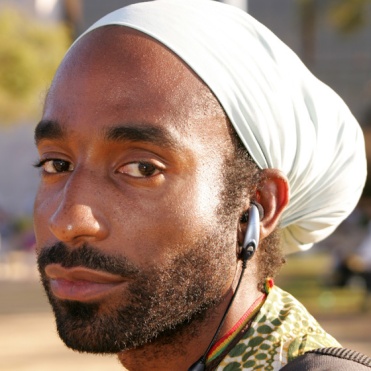 man with ear plugs and white turban head covering