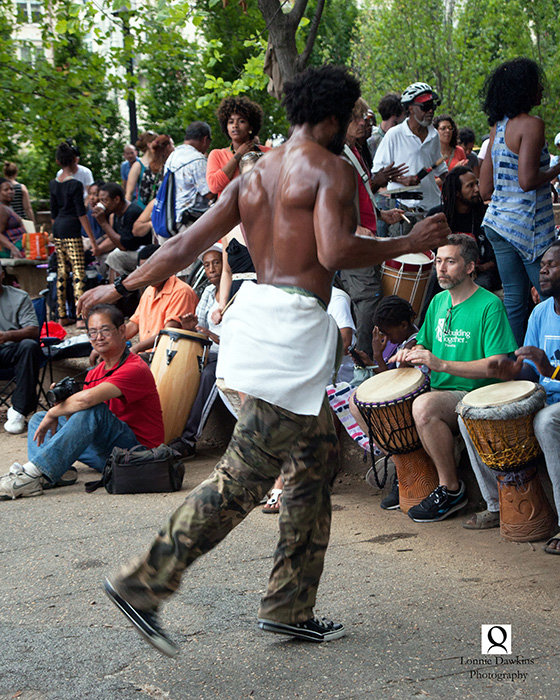 5b-Shirtless black male dancing to beat of drummers in park