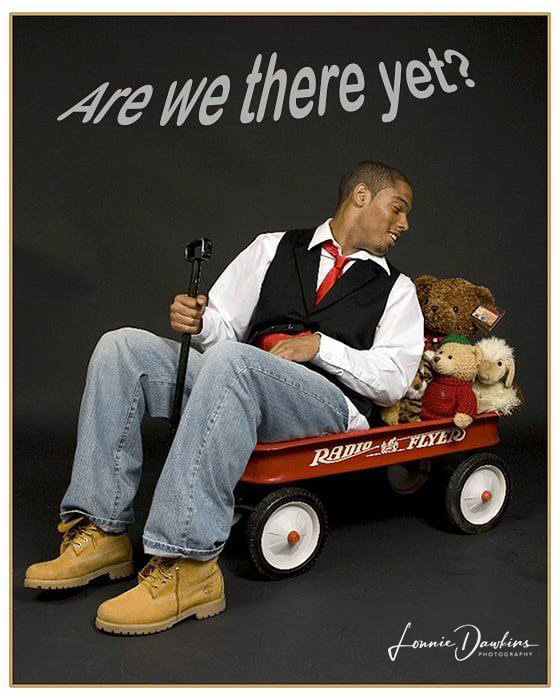 Man in little red wagon filled with stuffed animals