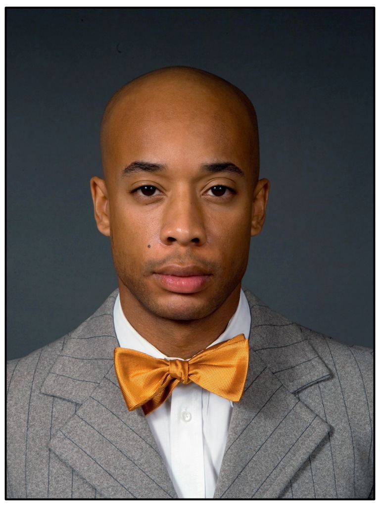 Black male model in suit with gold bowtie and bald